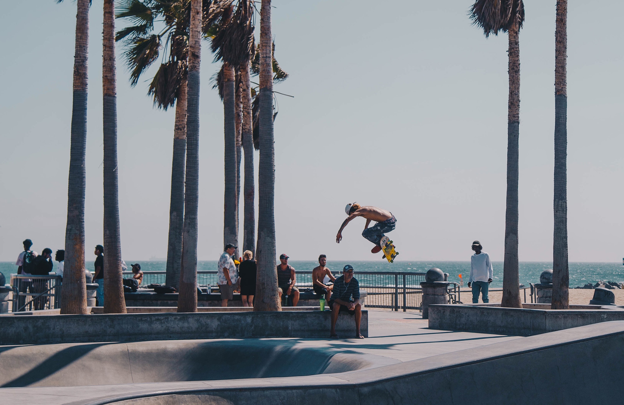 en mandlig studerende i los angeles skater på en rampe på stranden