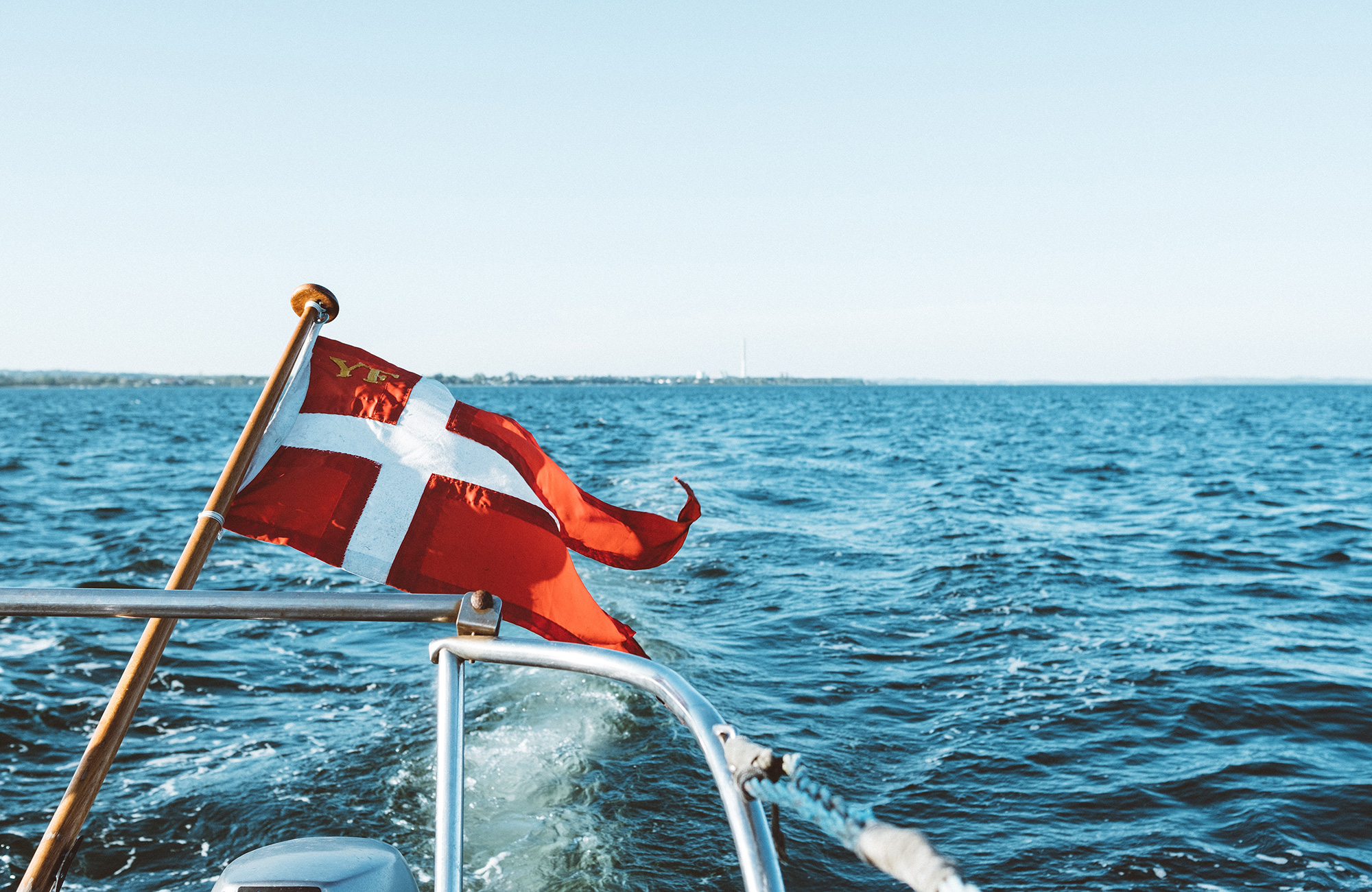 det danske flag svajer i vinden på en båd på havet