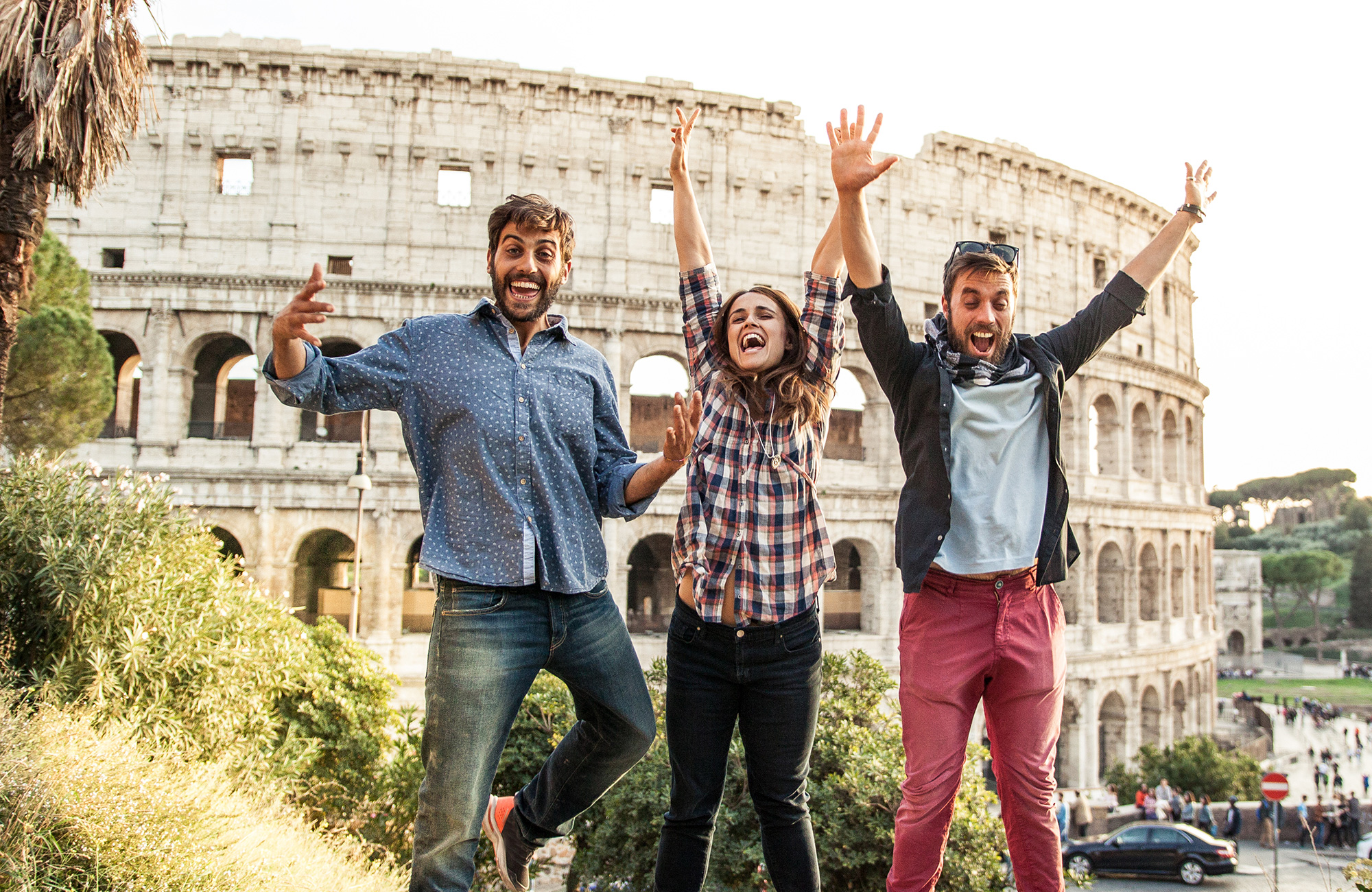 tre unge hopper foran colosseum på deres studietur til rom og studierejse til rom