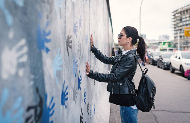 en ung studerende på studietur til berlin sætter hænderne på muren