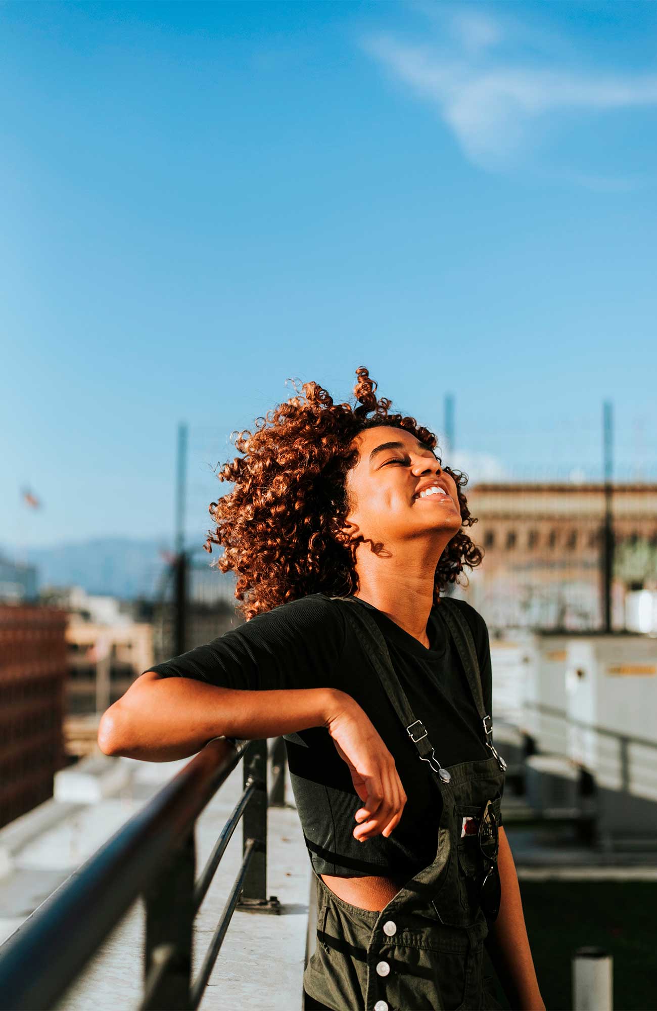 curly-girl-standing-balcony-terrace-sunlight