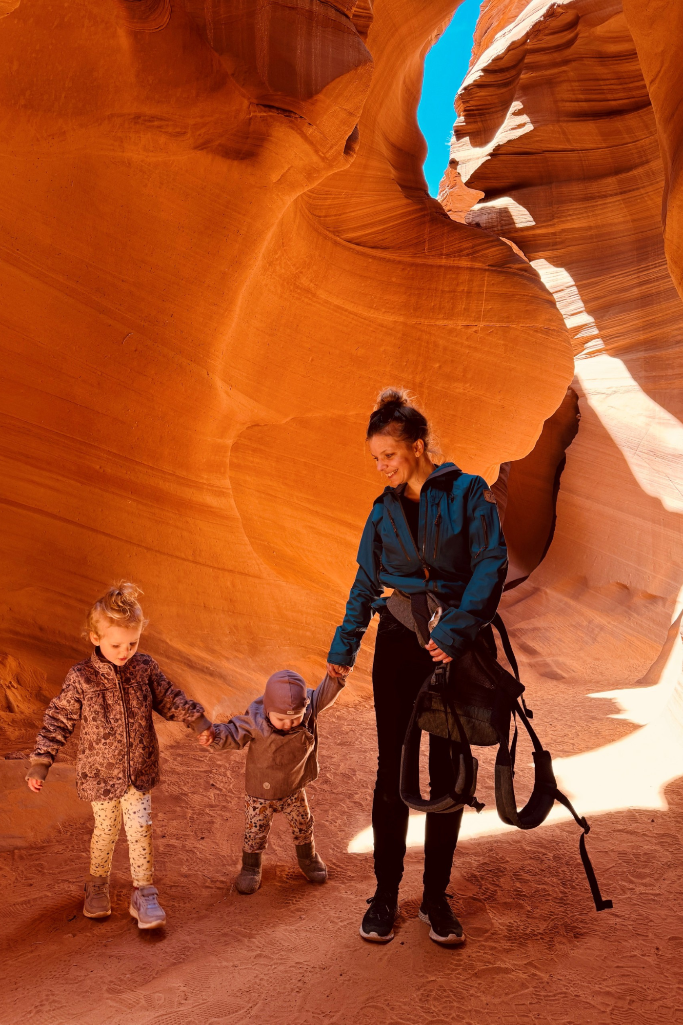 En kvinde og to små børn mellem orangerøde klipper i Arizona, USA.