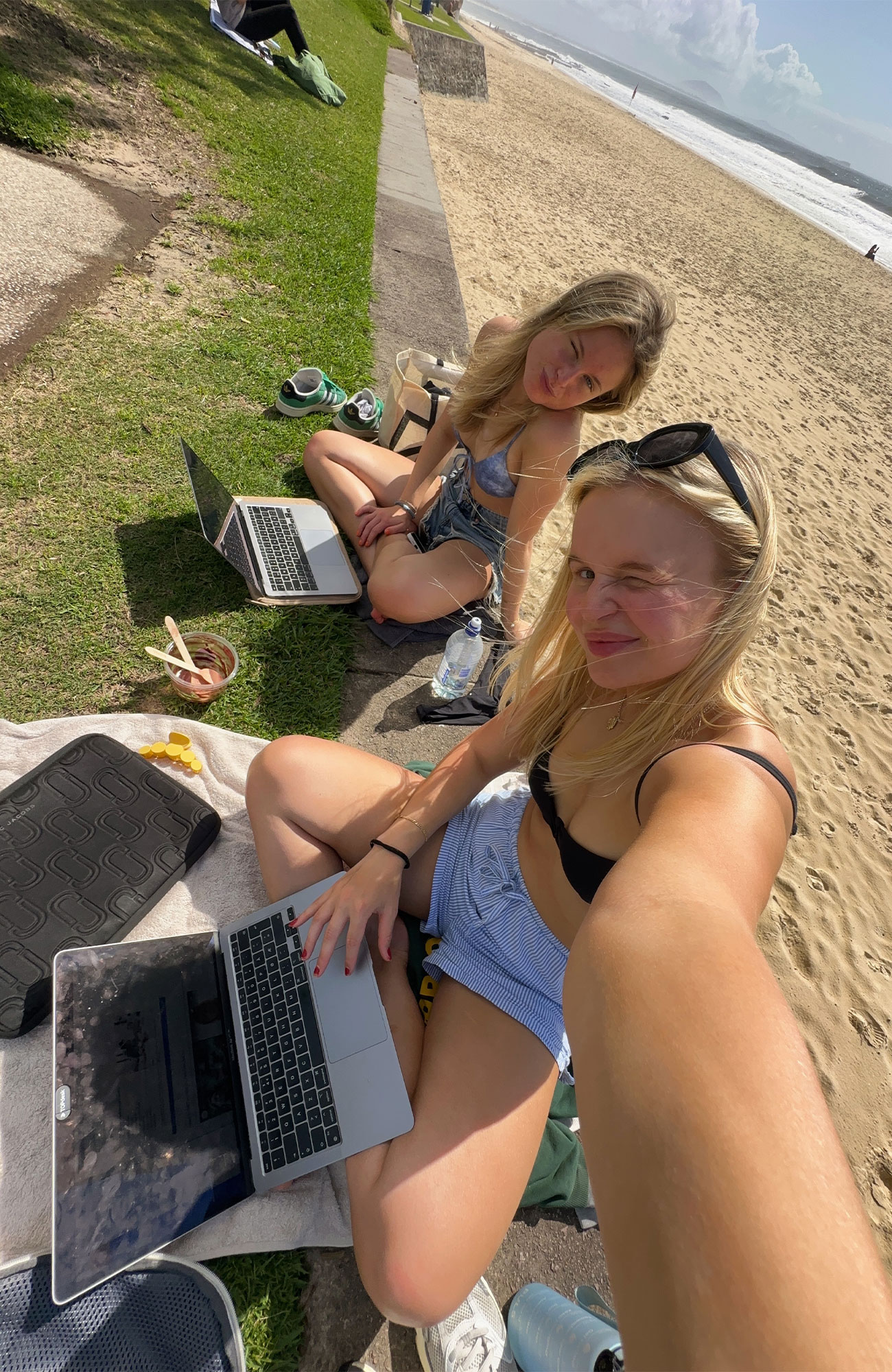 studerende i udlandet sidder med deres computer ved en strand